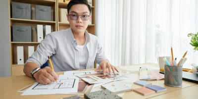 Interior designer working on new project, checking blueprints and collecting samples of materials
