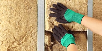 Worker installing thermal insulation material on wall, closeup