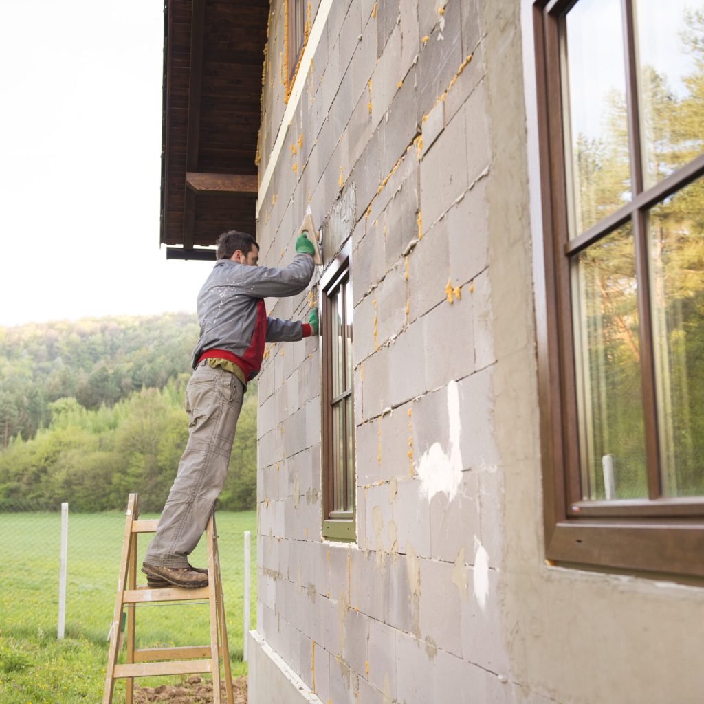 Plasterer spreading out plaster with trowel around the windows