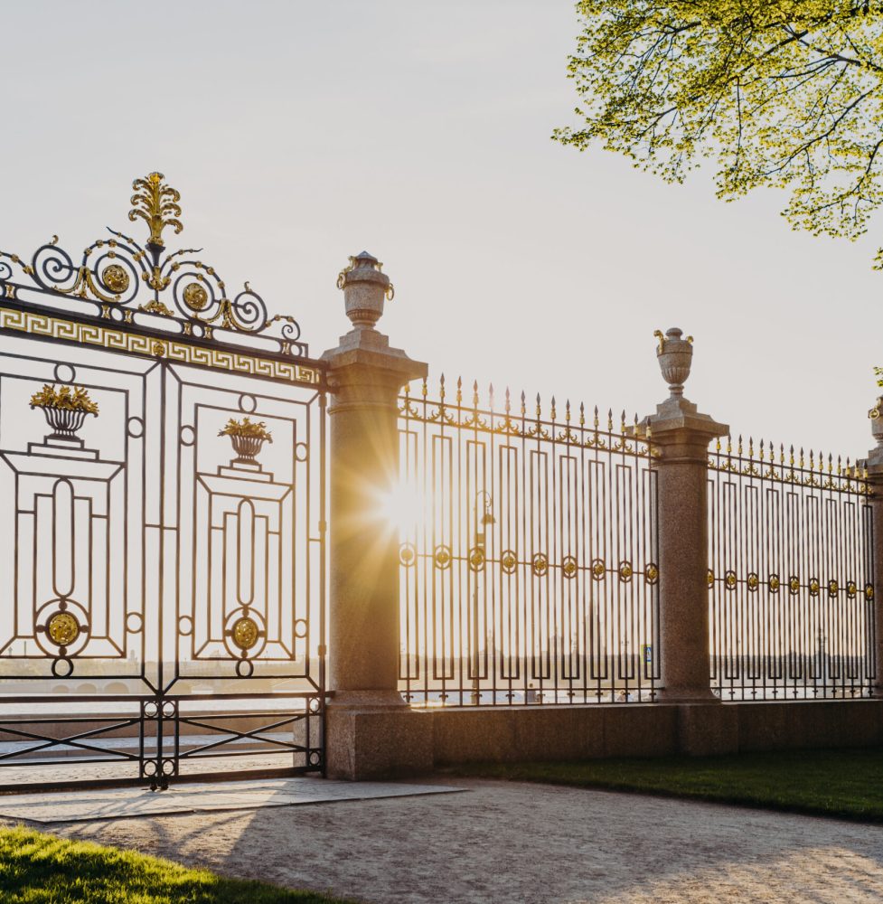 Gates of Summer Garden in Russia, Saint Petersburg. Sunny spring day. Green beautiful trees and grass. Fence with gate. Masterpiece of architecture