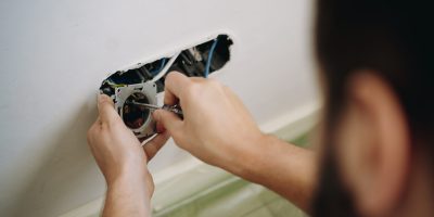 man installing socket. electrician hands holding screwdriver. Renovation, repair concept. Image with selective focus