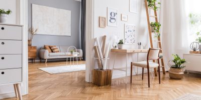 Creative composition of stylish scandi home office interior design with mock up poster frames, wooden desk, chair, plants and accessories. Neutral walls, parquet floor. Template.